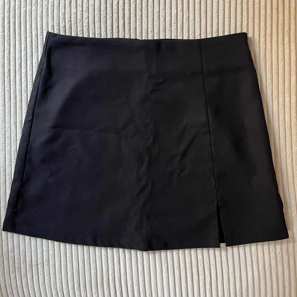 Size 4 black mini skirt with slit and zipper back. MVN from Billy J Boutique.